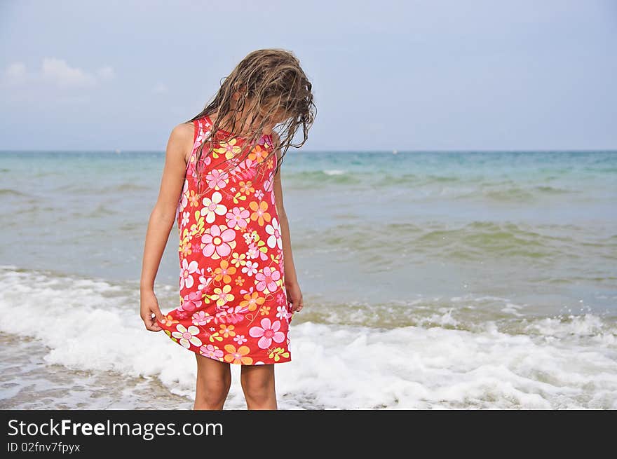 Sweet beautiful girl in a bright dress looks on the sea. Sweet beautiful girl in a bright dress looks on the sea