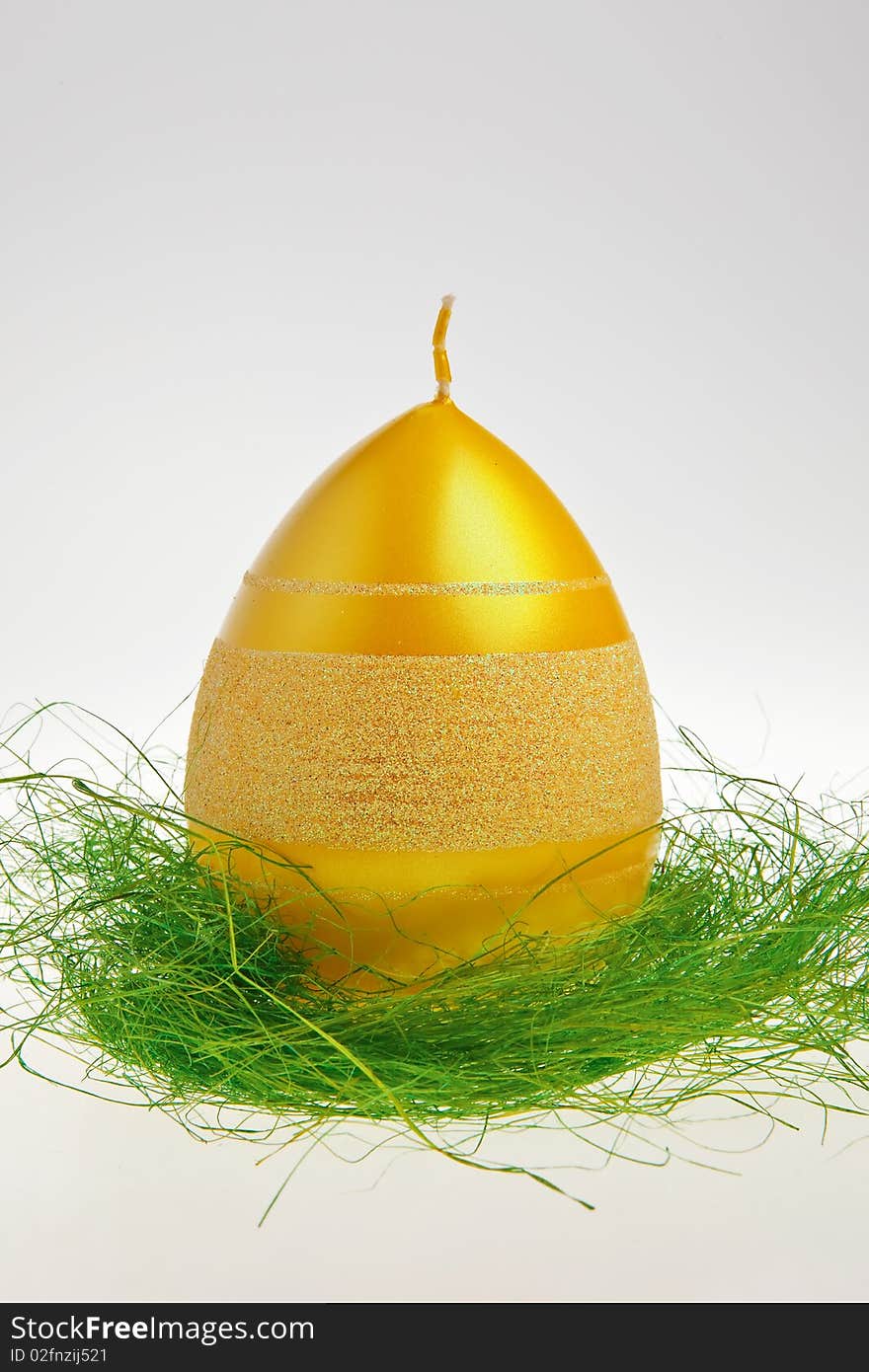 Yellow egg shaped candle on green decoration isolated over white background. Yellow egg shaped candle on green decoration isolated over white background.