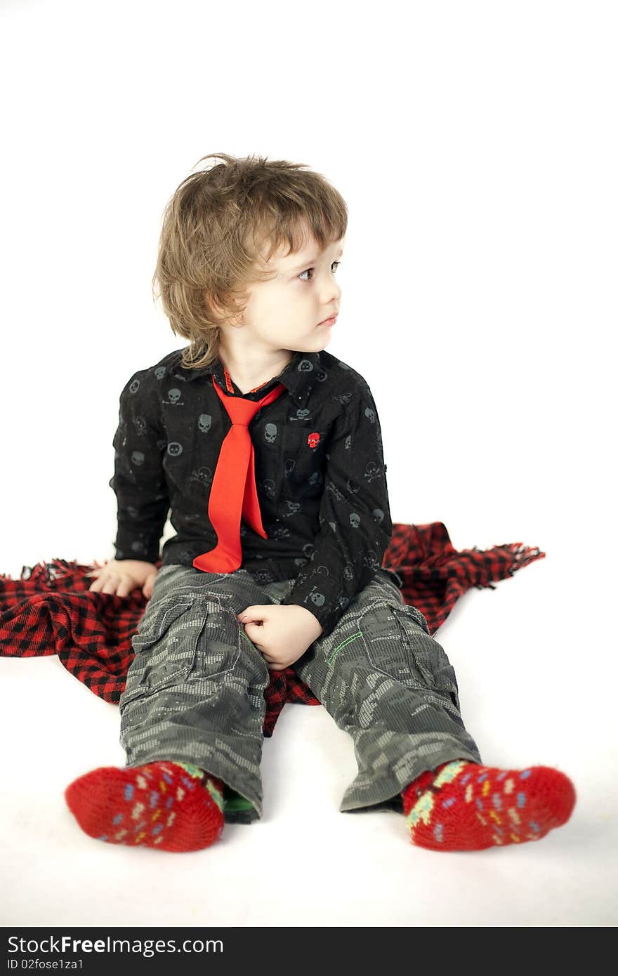 Cute child sitting on a red scarf and looking away. Cute child sitting on a red scarf and looking away