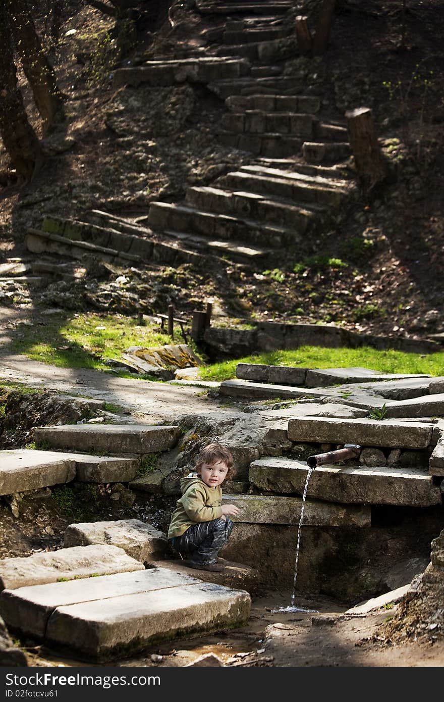 Little boy sitting near a spring