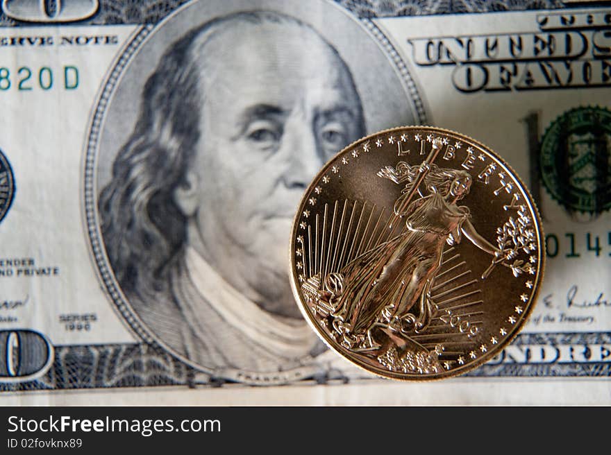 Stack of gold coins on 100 note. Focus on Franclin's eye and coin. Stack of gold coins on 100 note. Focus on Franclin's eye and coin