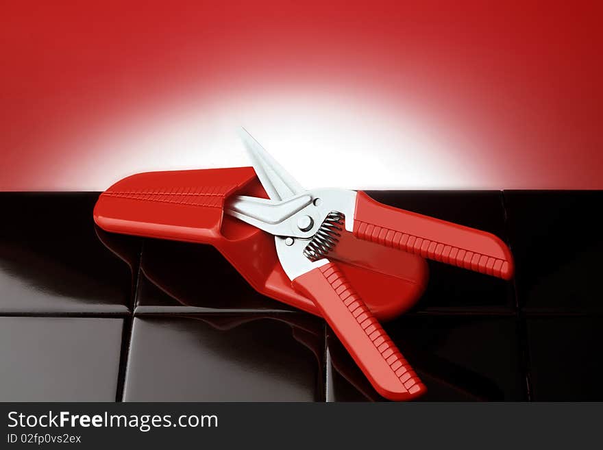 Red pliers on black tiles. Red pliers on black tiles