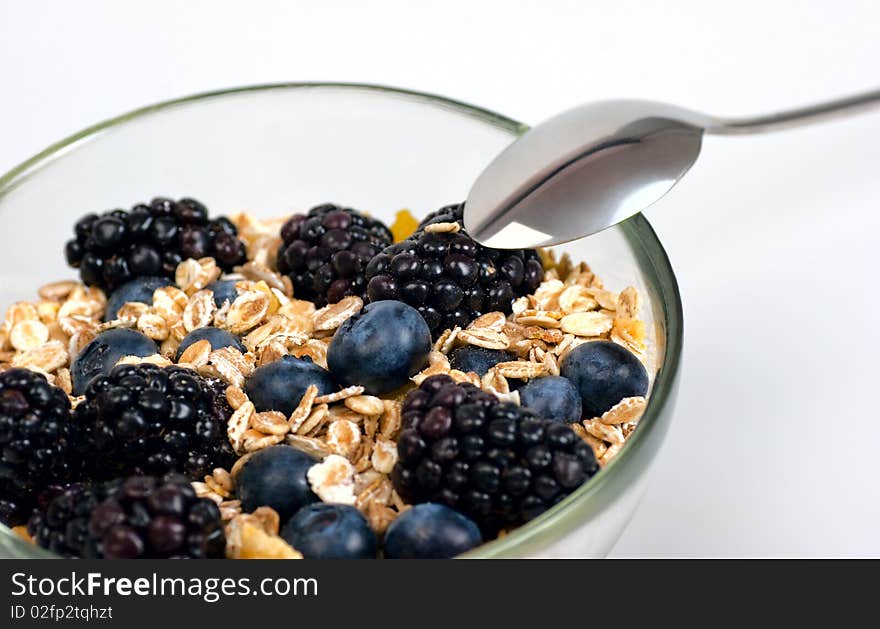 A glass bowl full of muesli, corn flakes, blackberries and blueberries. Selective focus. A glass bowl full of muesli, corn flakes, blackberries and blueberries. Selective focus.