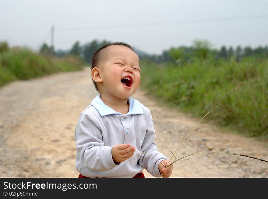 It is a laughing chinese baby on the countryside road. It is a laughing chinese baby on the countryside road.