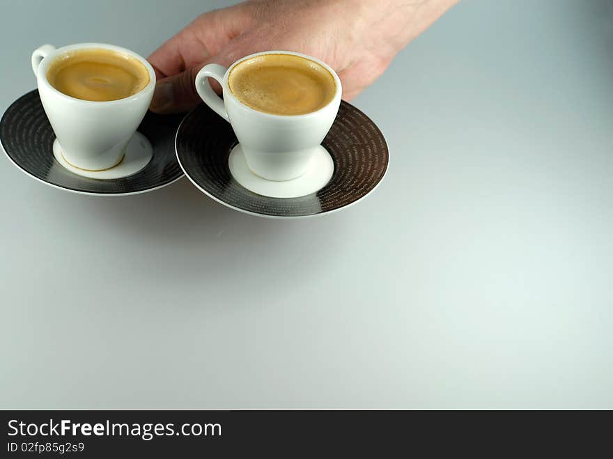 Hand serving two espresso cups