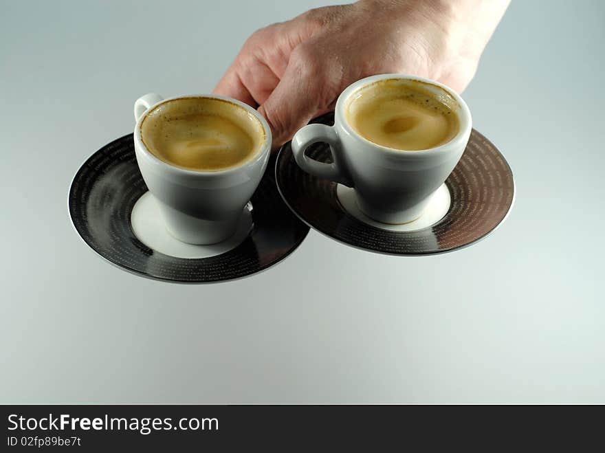 Hand serving two espresso cups