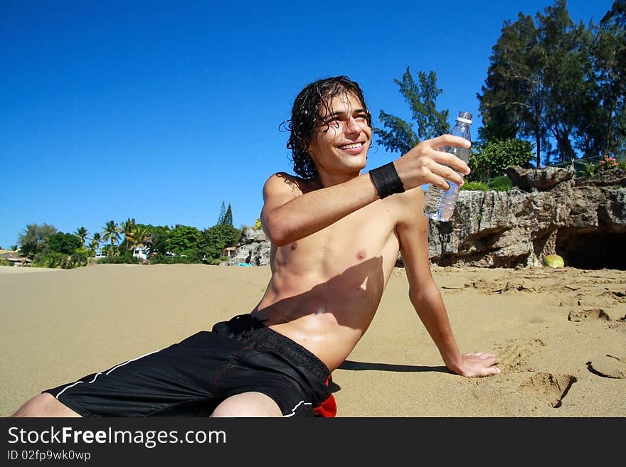 Man with bottle of  water in hand on beach