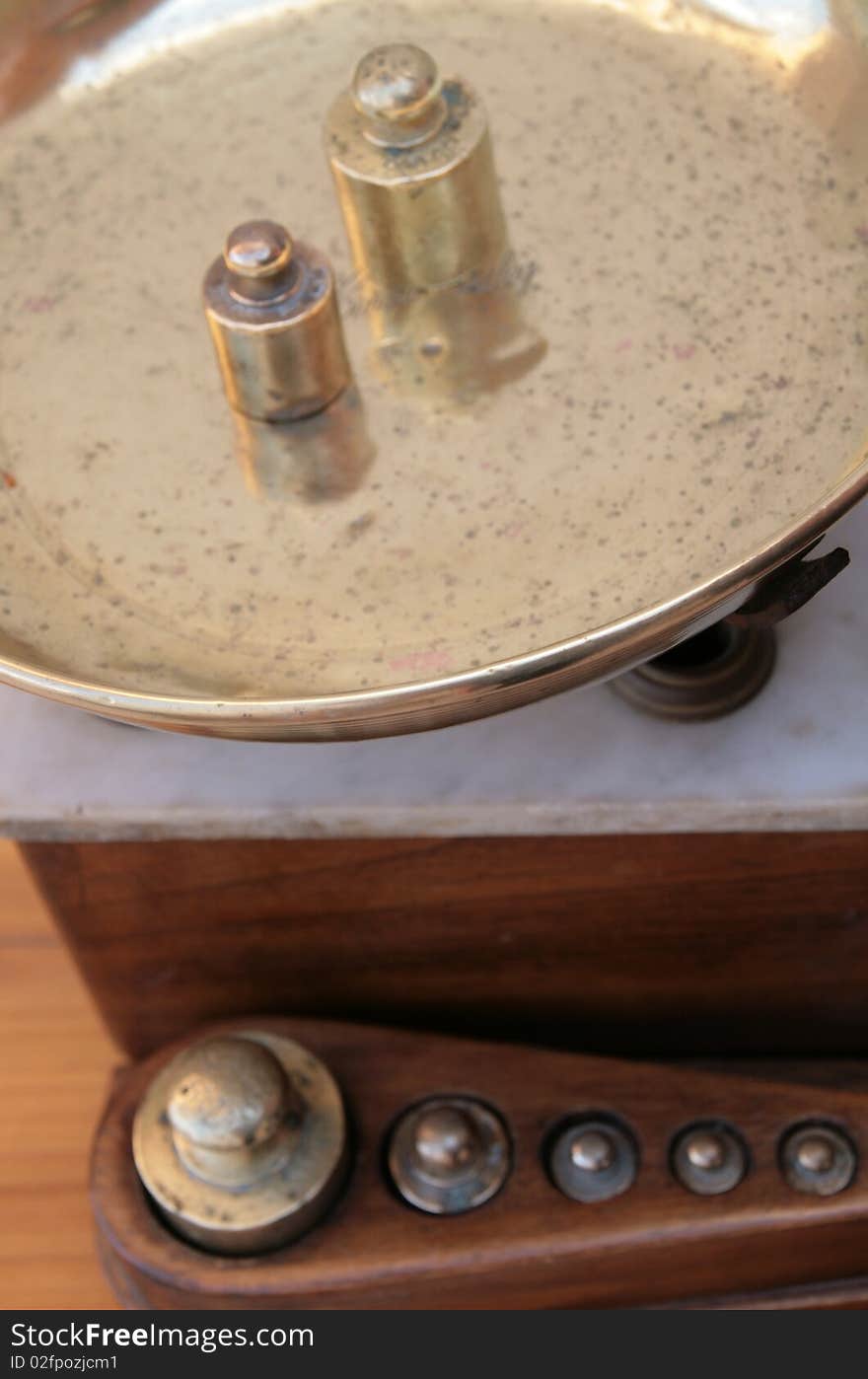 Close-up of an antique scale with brass pans and weights and a wood and marble base. Close-up of an antique scale with brass pans and weights and a wood and marble base