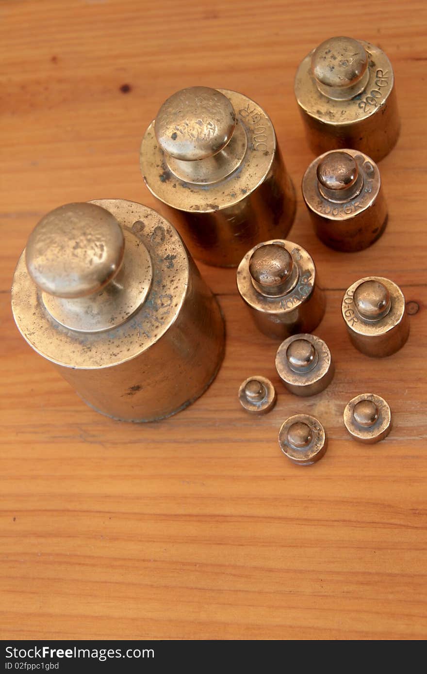 Antique weights from an old scale, made of brass, on a wooden background. Antique weights from an old scale, made of brass, on a wooden background