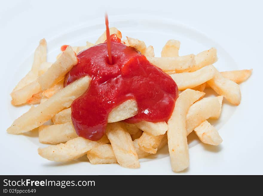 French fries being drenched in ketchup on white plate. French fries being drenched in ketchup on white plate