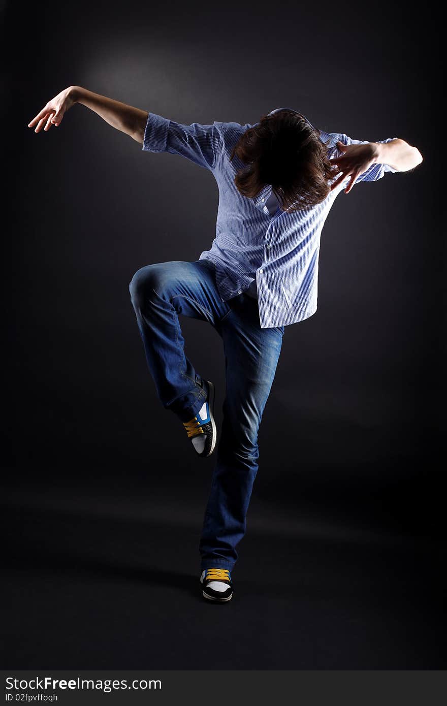 Young man modern dancer in action against black