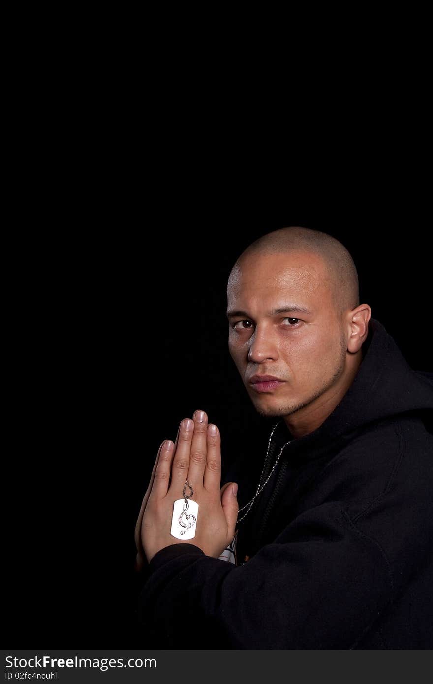 A young asian man with a hoddie is praying over black. A young asian man with a hoddie is praying over black