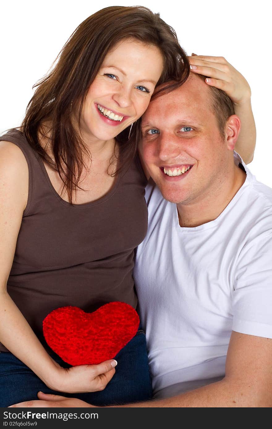 Young couple sitting in a chair holding a heart. Young couple sitting in a chair holding a heart.