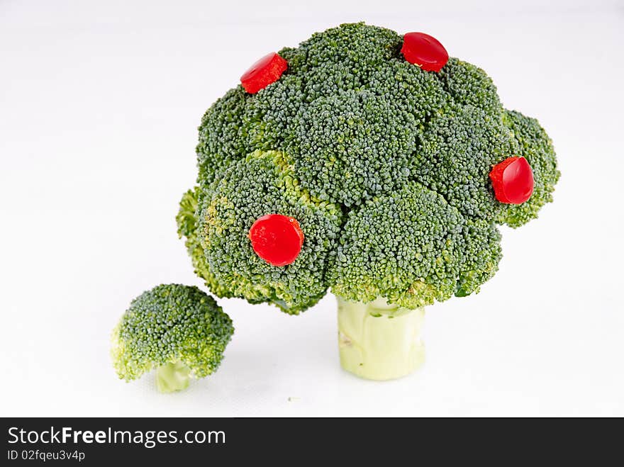 Broccoli tree with some pepper fruits on white background - symbol of growth and crop