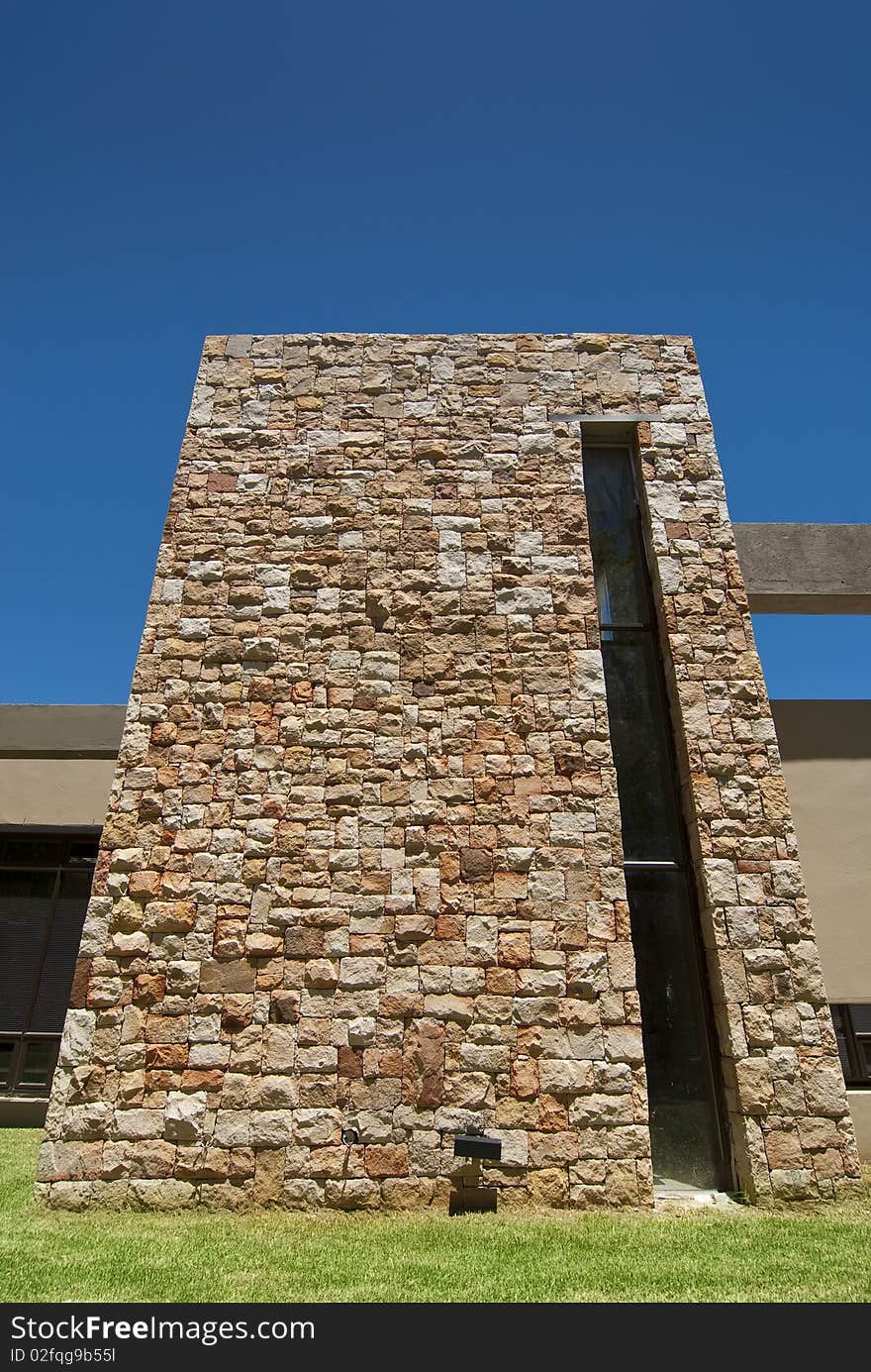 Exterior of moderen houe with an emphasis on stone details, with a clear blue sky overhead. Exterior of moderen houe with an emphasis on stone details, with a clear blue sky overhead