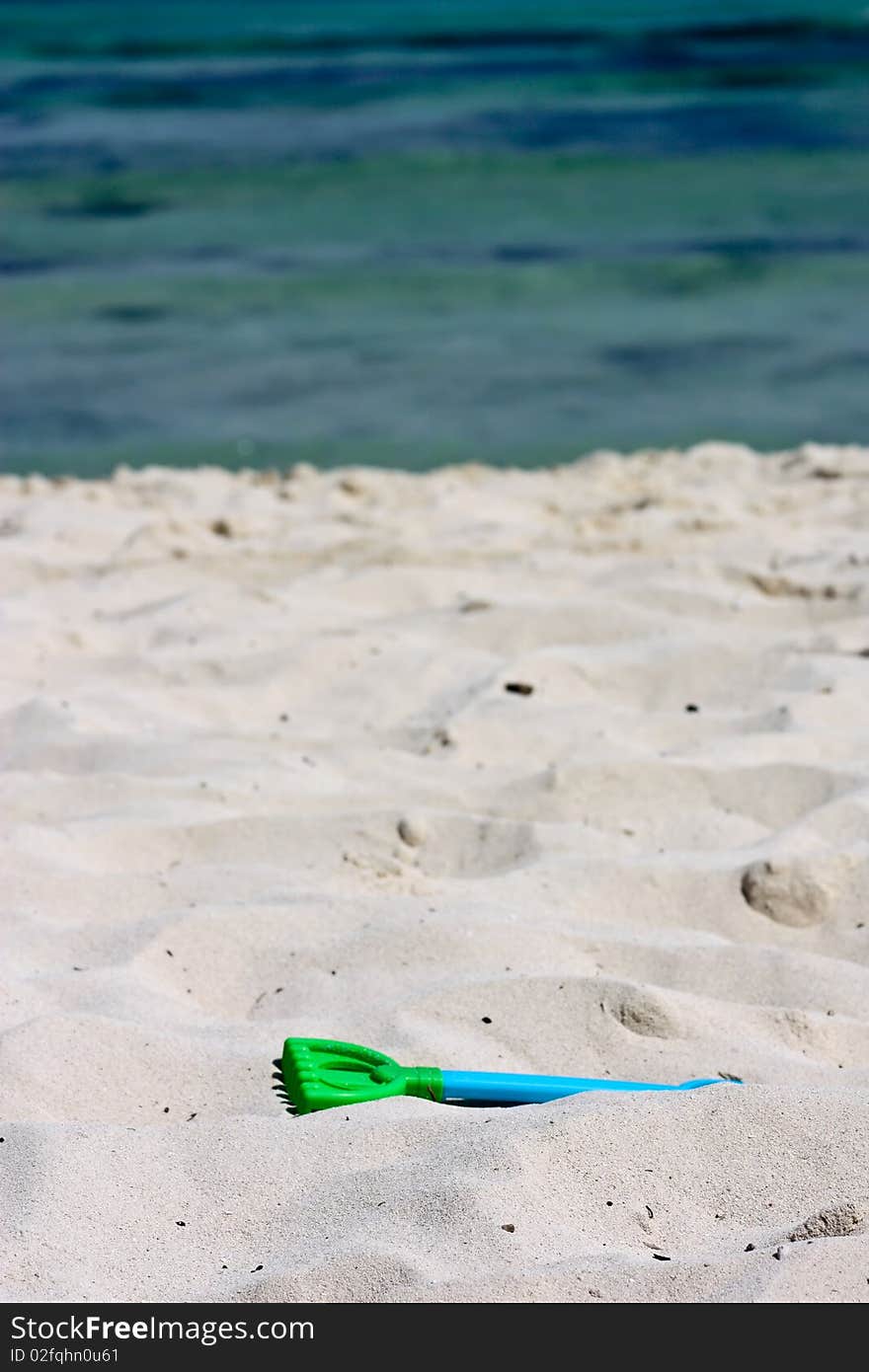 Plastic rake toy on beach near ocean