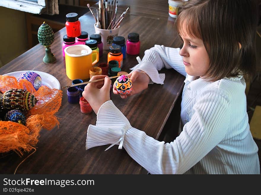 Schoolgirl is paint of easter egg by paintbrush