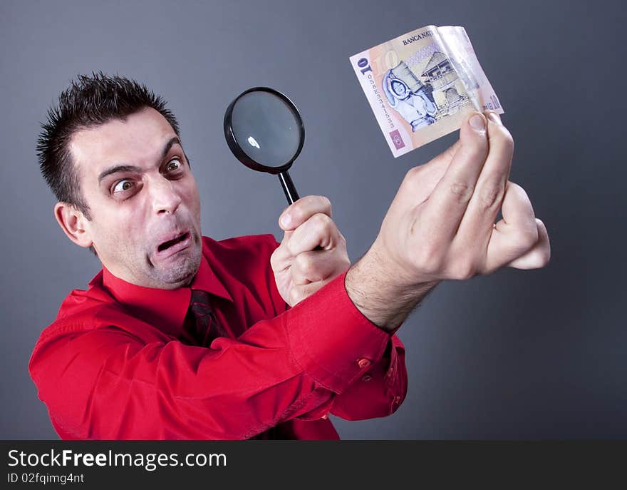 Funny businessman looking at banknote with magnifying glass