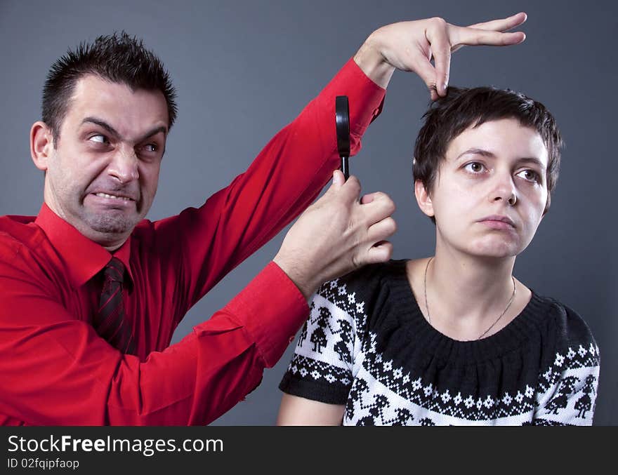 Man examining woman's hair with magnifying glass