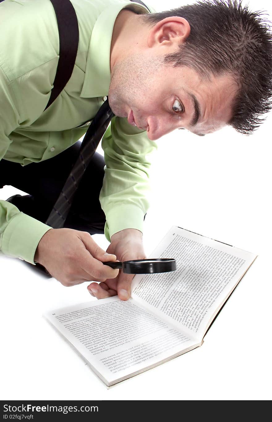 Funny businessman reading a book with magnifying glass