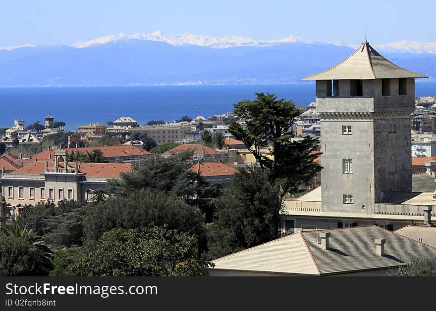 An old beautiful tower over a blue sea and snowy mountains. An old beautiful tower over a blue sea and snowy mountains.