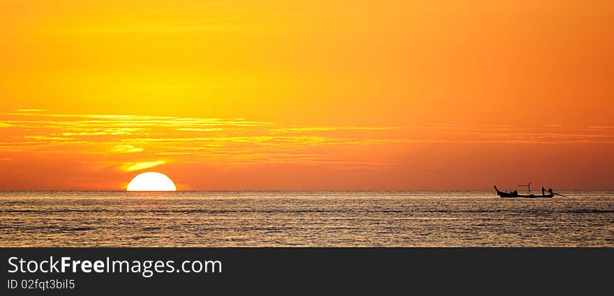 Sillhouette of a boat against the orange sunset