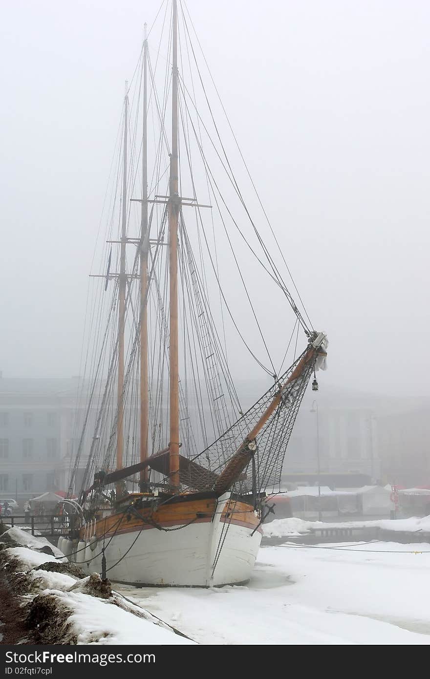 Old sailboat in foggy spring morning by pier