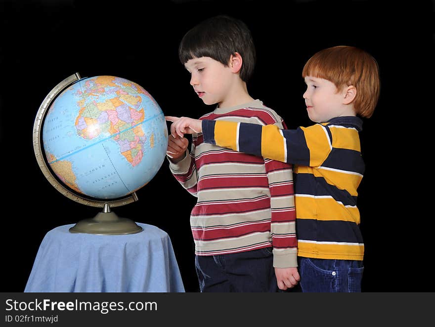 Two young boys identify various countries on the globe. Two young boys identify various countries on the globe