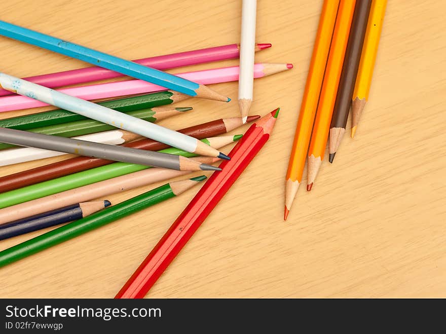 Colored Pencils Scattered on a Wood Background