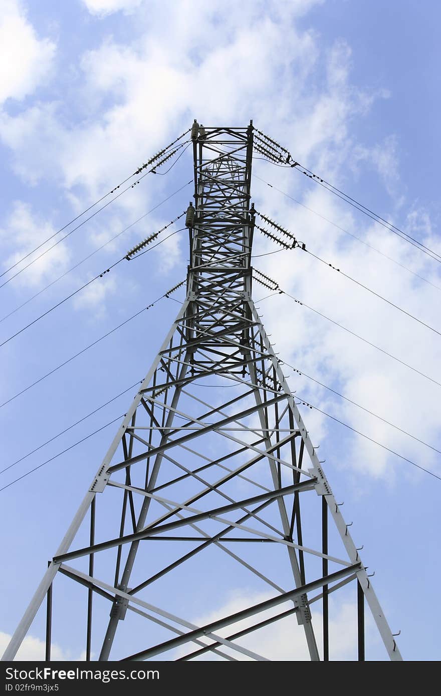 Support metal high-voltage with isolators and wires on a background of the blue sky with clouds.