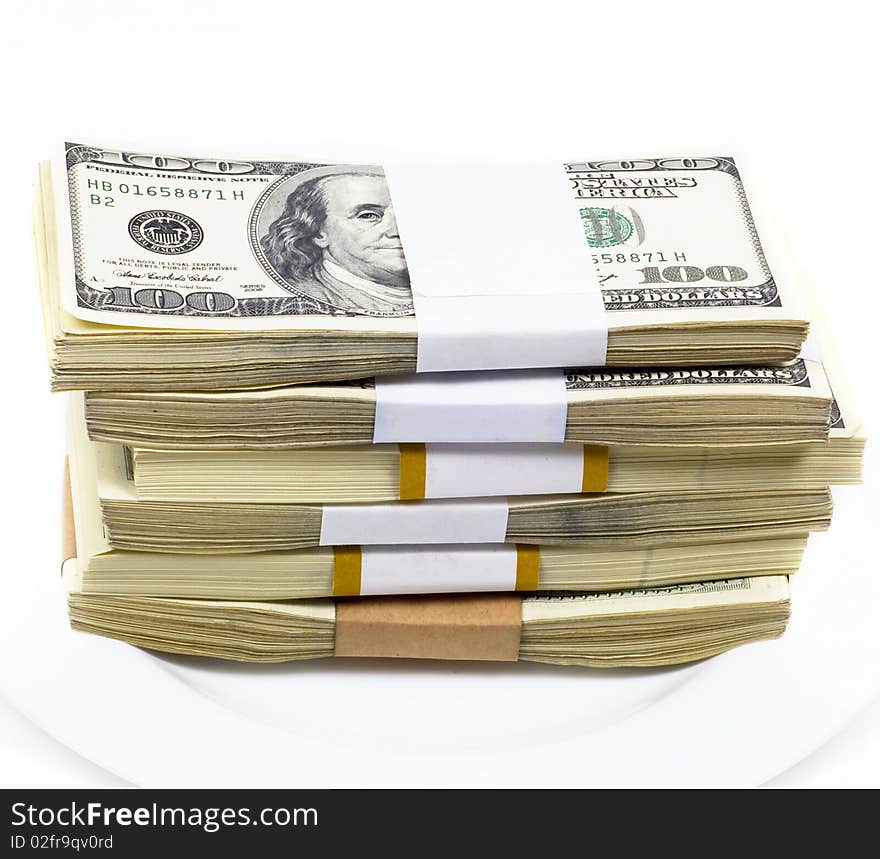 Pile of dollar denominations lies on white plate on white background. Pile of dollar denominations lies on white plate on white background