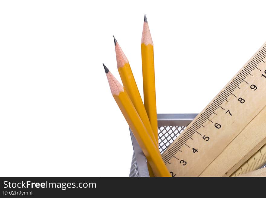 Pencils and wooden rulers in a support on a white background. Pencils and wooden rulers in a support on a white background