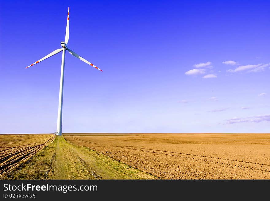 Windmill conceptual image. Windmills on plowed field.