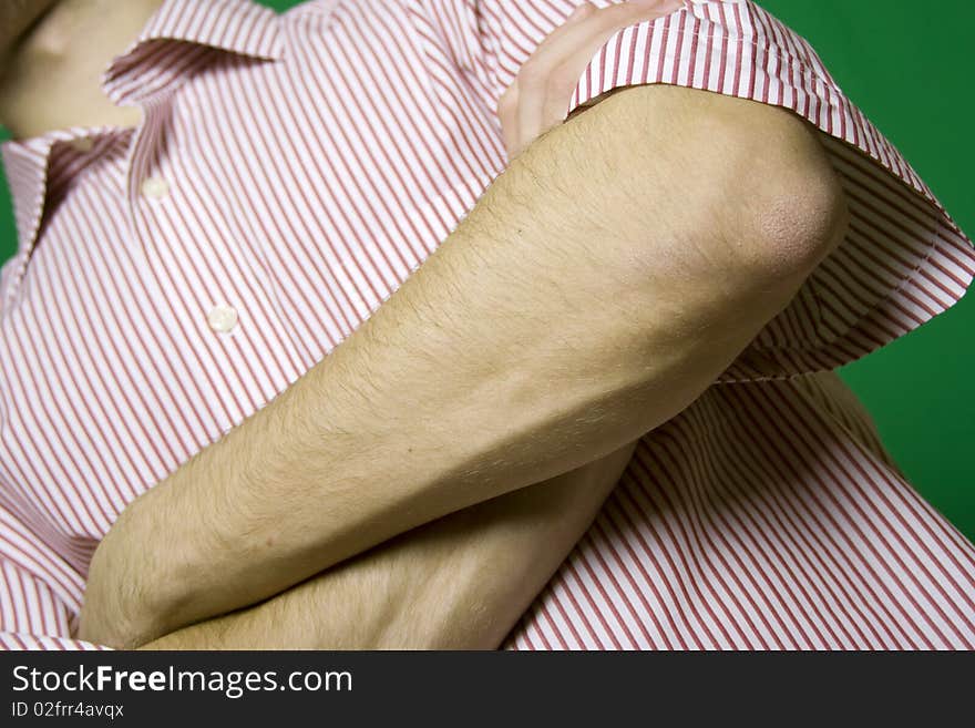 A young man on a green background hand in the foreground are crossed. A young man on a green background hand in the foreground are crossed