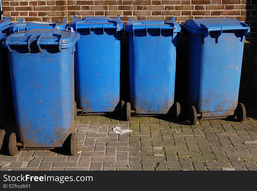 A collection of blue plastic garbage containers