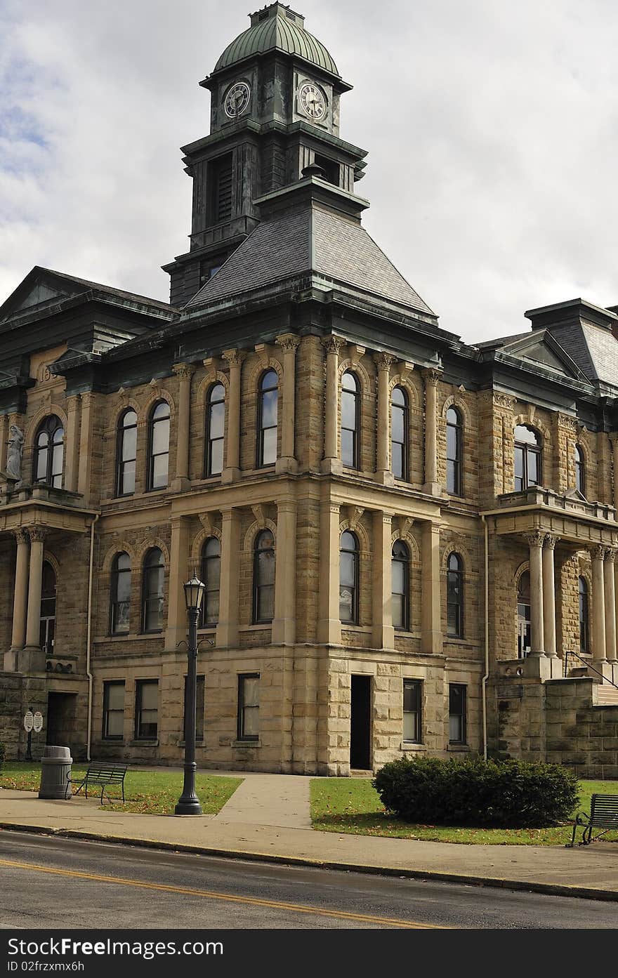 Low angle view of an old stone municipal building with a clock tower. Vertical shot. Low angle view of an old stone municipal building with a clock tower. Vertical shot.