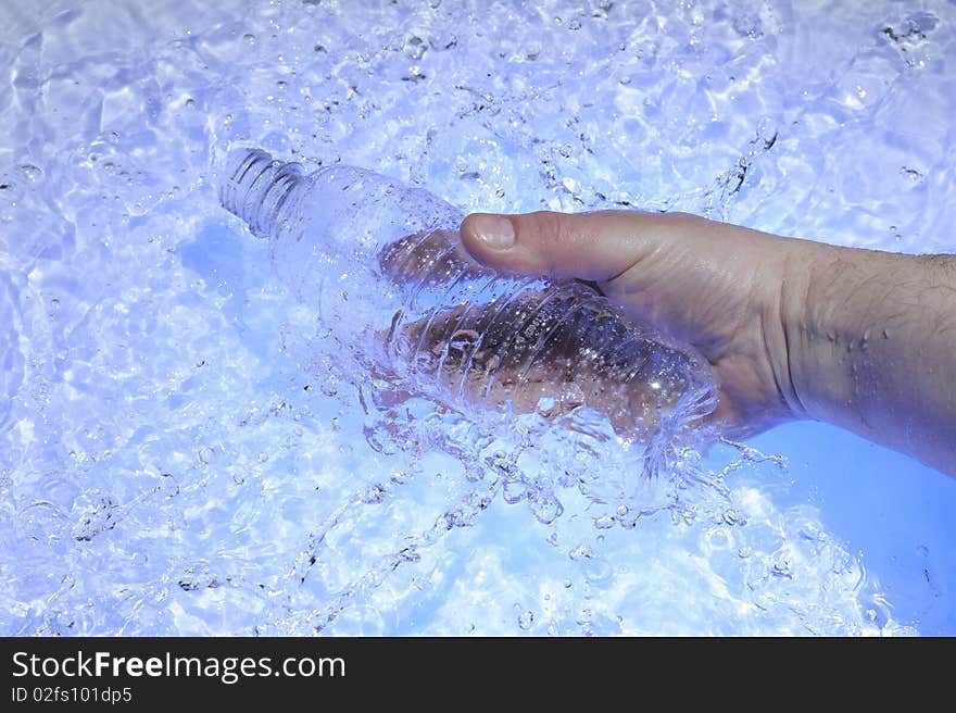 Hahd with plastic bottle in blue water