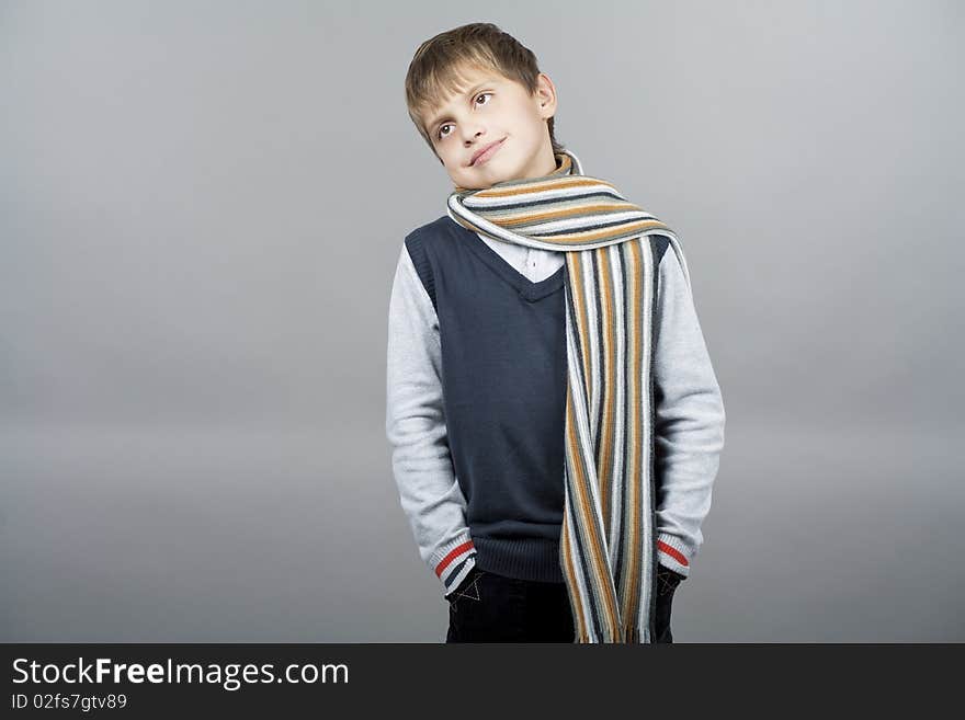 Caucasian teenager boy with natural pretty smile and dreaming facial expression weating colorful scarf and standing isolated over gray background with copyspace. Caucasian teenager boy with natural pretty smile and dreaming facial expression weating colorful scarf and standing isolated over gray background with copyspace