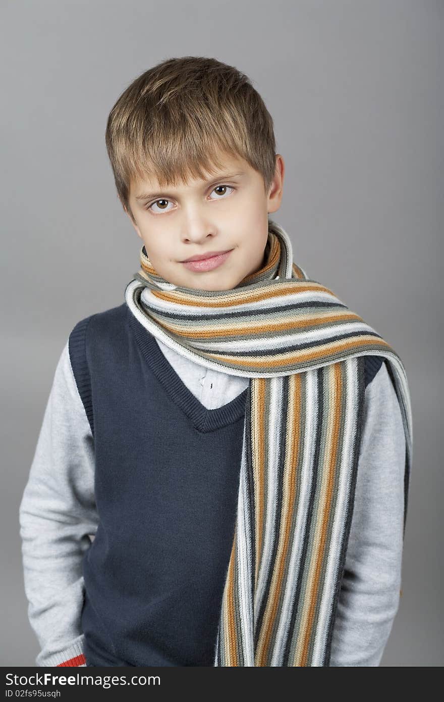 Cute and happy young caucasian teenager boy with elegant colorful scarf around and natural light smile standing isolated over gray background. Cute and happy young caucasian teenager boy with elegant colorful scarf around and natural light smile standing isolated over gray background