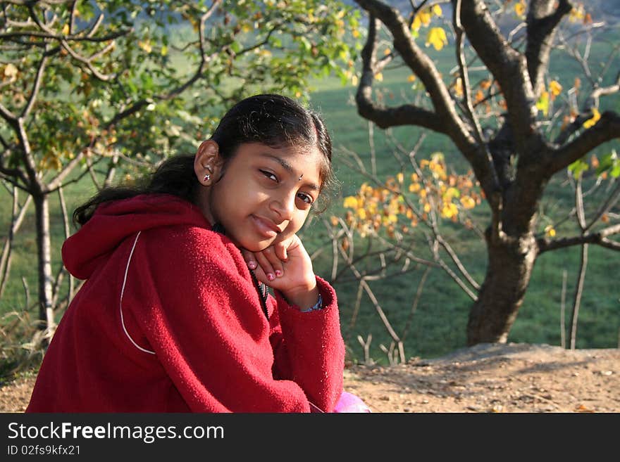 Indian girl in red sweater sitting in a park. Indian girl in red sweater sitting in a park