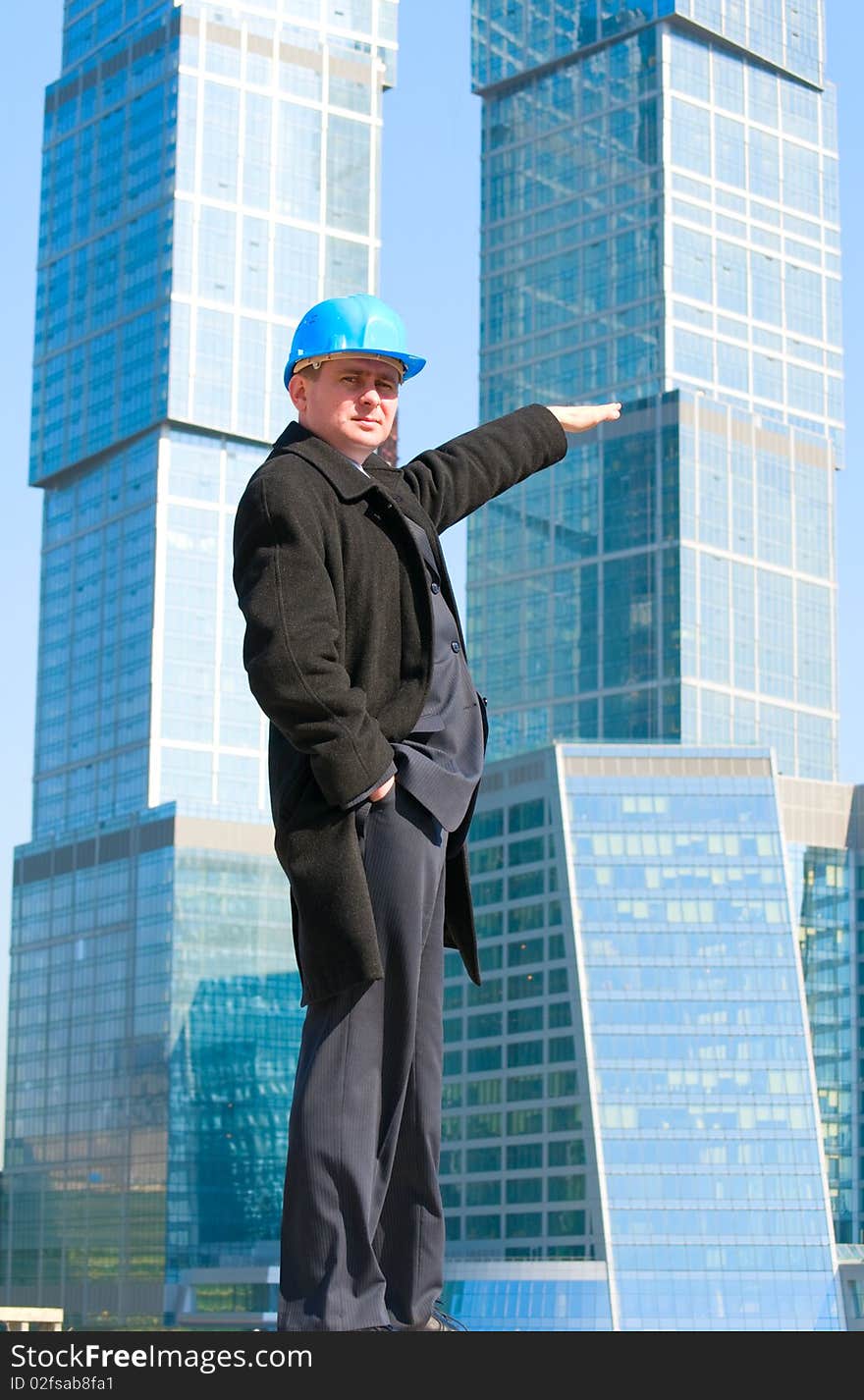 An engineer with blue hard hat standing confidently on sky background