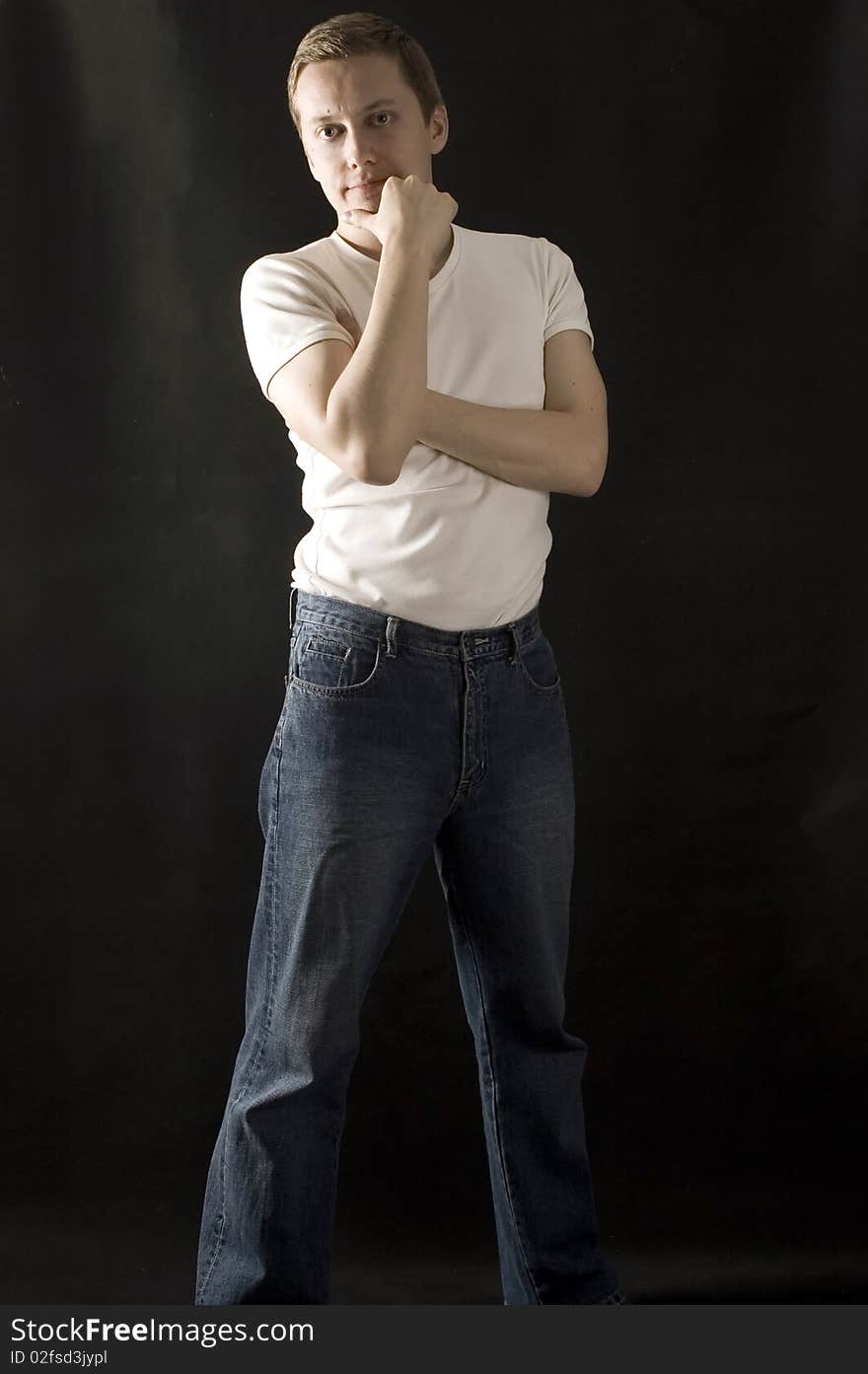 Young, European male model, wearing simple white t-shirt and jeans with black background. Young, European male model, wearing simple white t-shirt and jeans with black background.