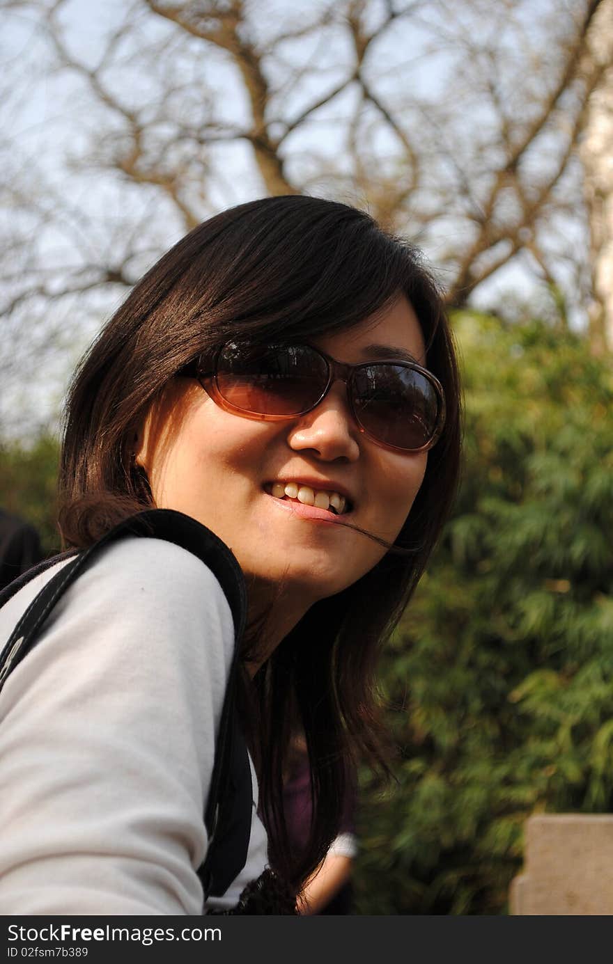 Chinese girl with sunglasses, green trees background