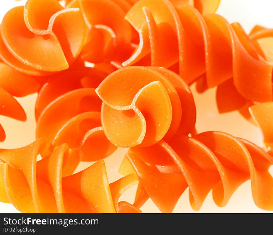 Orange pasta spirals against a white background.