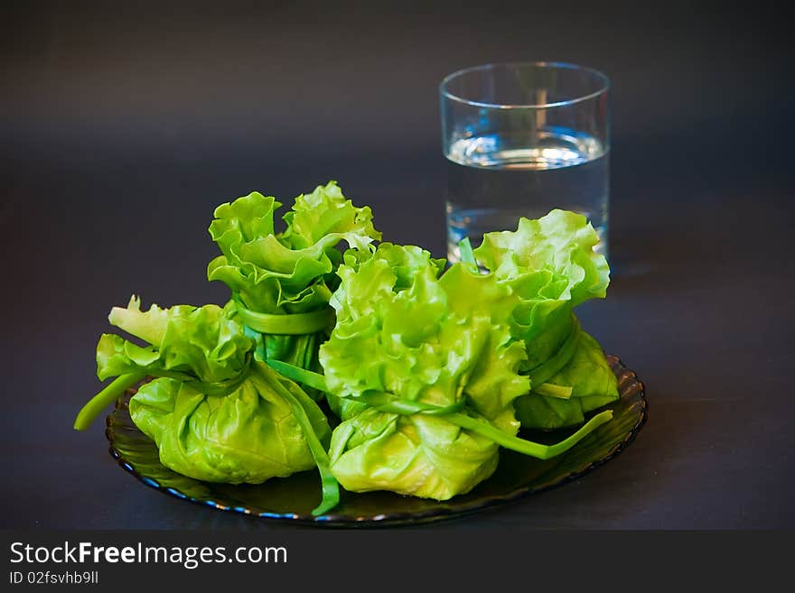 Close-up bags made of lettuce filling with cheese and a glass of water. Close-up bags made of lettuce filling with cheese and a glass of water