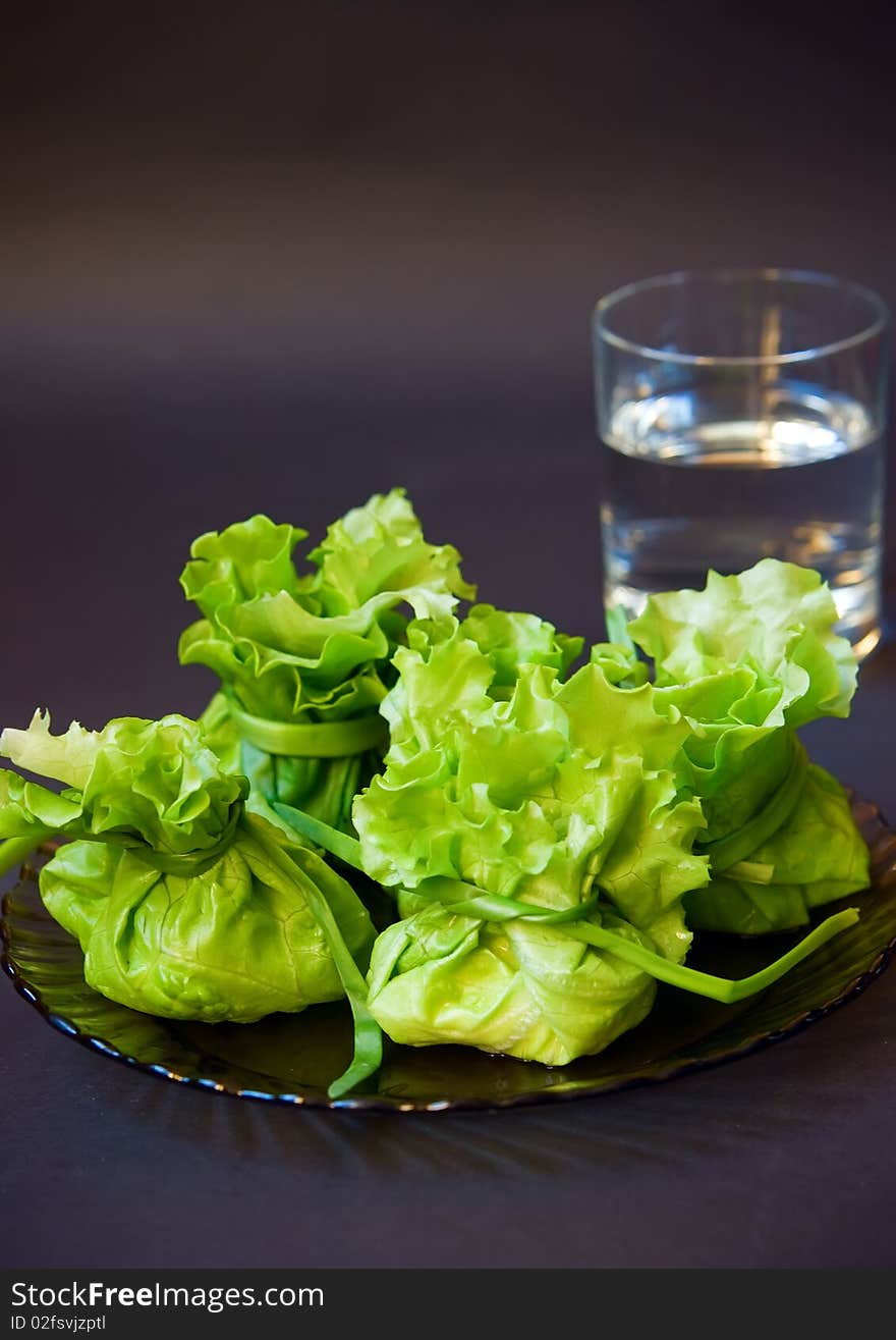 Close-up bags made of lettuce filling with cheese and a glass of water. Close-up bags made of lettuce filling with cheese and a glass of water