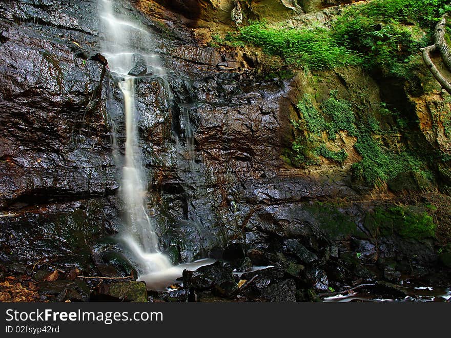 Beautiful multi-layered waterfall between vegetation.