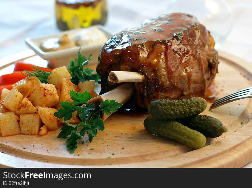 Pork with vegetables on a wooden support with sauce and mustard