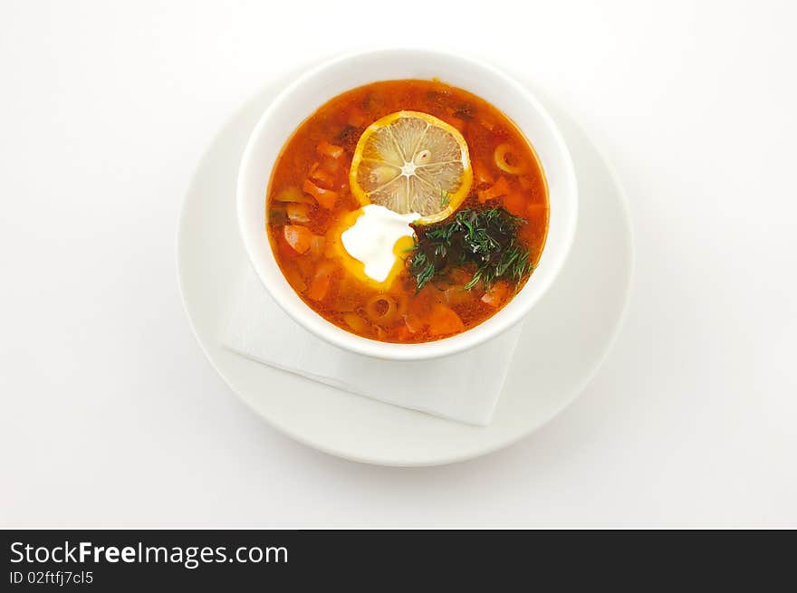 Soup with lemon and olives in a white plate on a white background