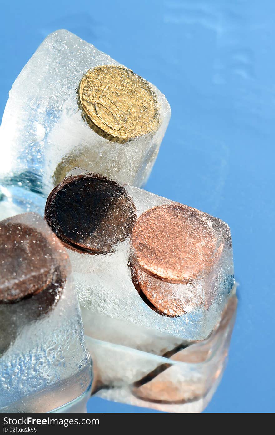 Coins inside ice cubes isolated on blue background. Coins inside ice cubes isolated on blue background